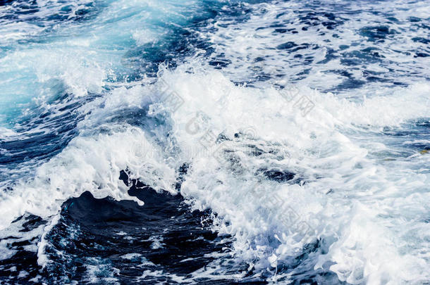 在阳光明媚的日子里，大西洋上有蓝色的水。 海上游轮引起的波浪、泡沫和尾流