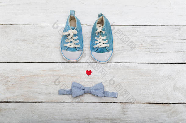 蓝色鞋子给一个小婴儿和一个蝴蝶领带在木制背景。 从上面看