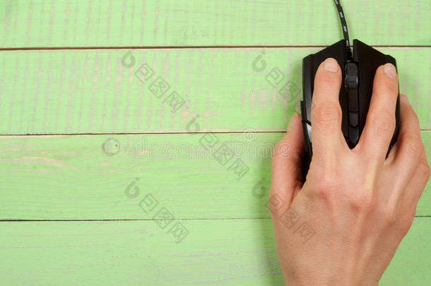 黑色电脑鼠标与一只手在绿色木制背景与复制空间为您的文本。 上面的风景