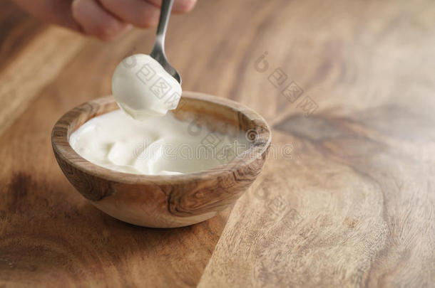 <strong>用勺子</strong>在桌子上的木碗里吃自制的有机酸奶