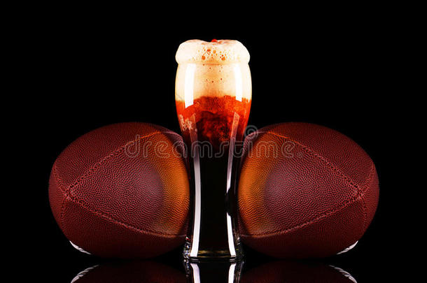 啤酒玻璃与深色啤酒泡沫和美国足球在黑色背景。