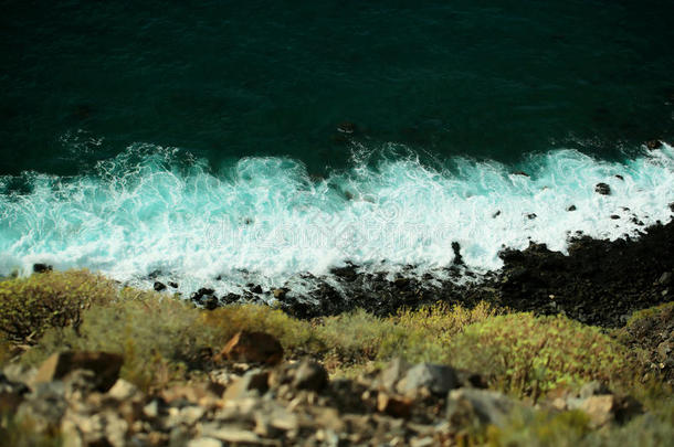 美丽的海蓝宝石海浪撞击黑色的岩石