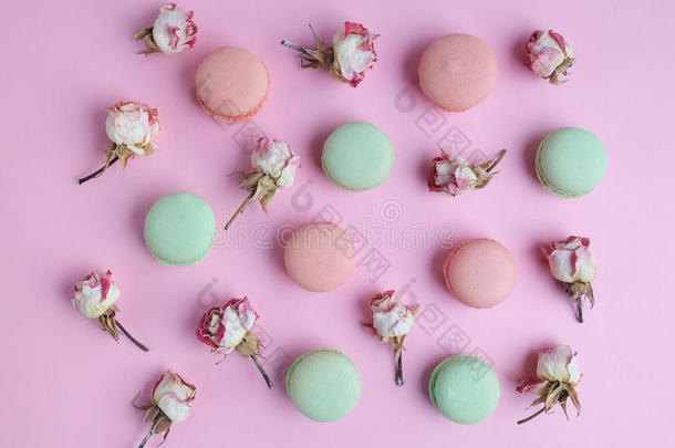 法国甜点马卡龙图案与干玫瑰花粉红色背景。 平躺