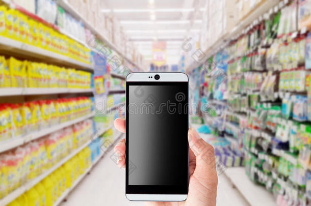 手持智能<strong>手机</strong>与模糊超市背景。