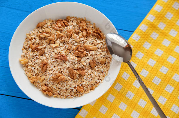一碗新鲜的燕麦片核桃在茶色乡村餐桌上，早餐吃热而健康的食物