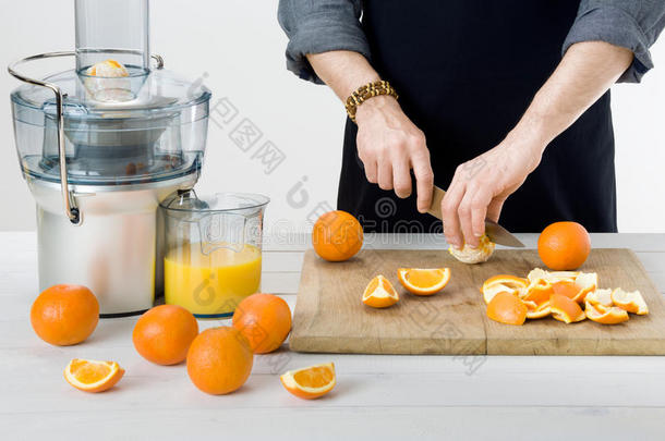 匿名男子穿着围裙，准备健康的橙汁，使用现代电动<strong>榨汁机</strong>，健康的生活方式概念