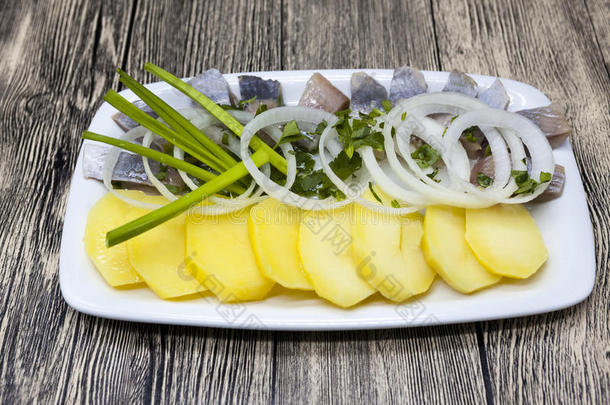荷兰国家开胃菜，青鱼加洋葱。 美味的冰岛鲱鱼与煮土豆和洋葱在盘子里。