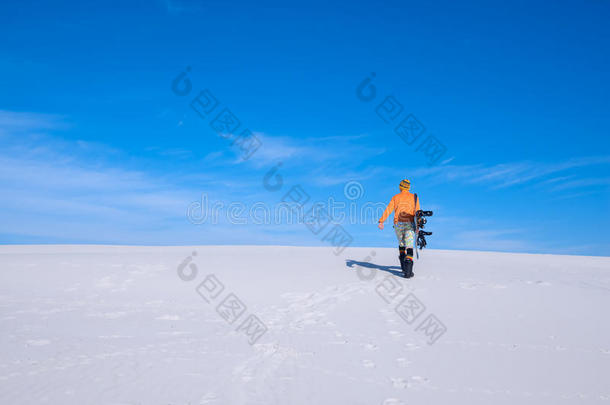 戴着滑稽帽的家伙拿着滑雪板走上沙丘