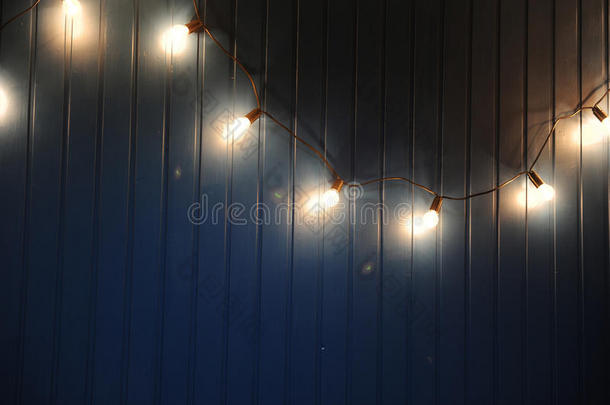 蓝色墙壁与复古花环的灯泡。 设计的纹理