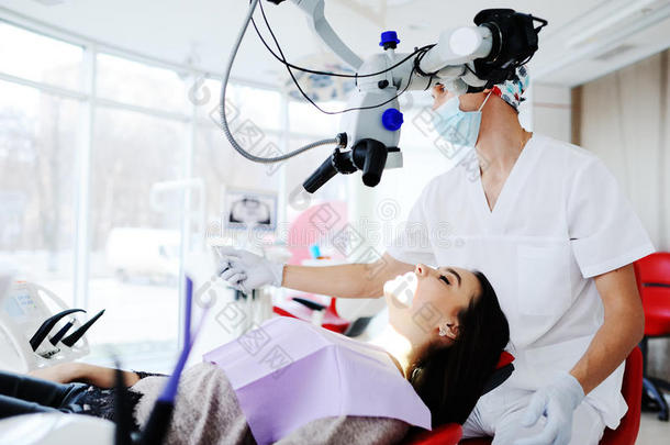 牙医通过牙科显微镜检查病人`牙齿