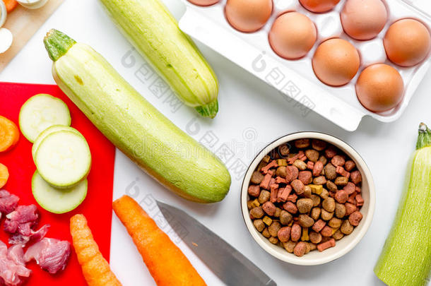 碗干狗粮，胡萝卜，胡瓜和肉桌背景顶部视图