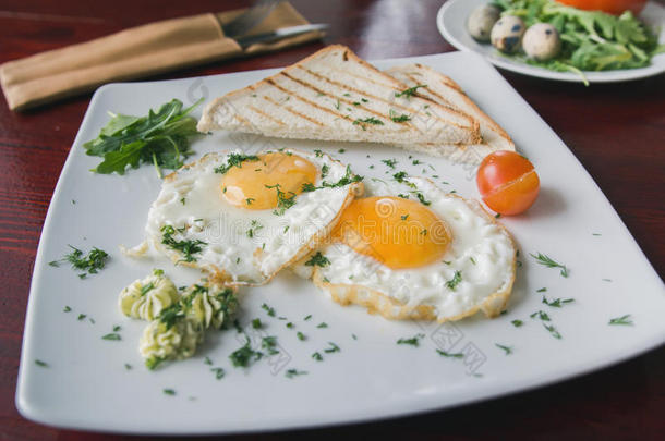煎鸡蛋在白色盘子与绿色和番茄樱桃-早餐