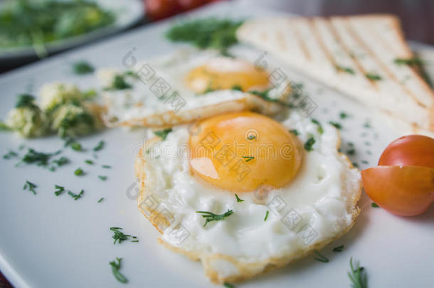 煎鸡蛋在白色盘子与绿色和番茄樱桃-早餐，宏观视图