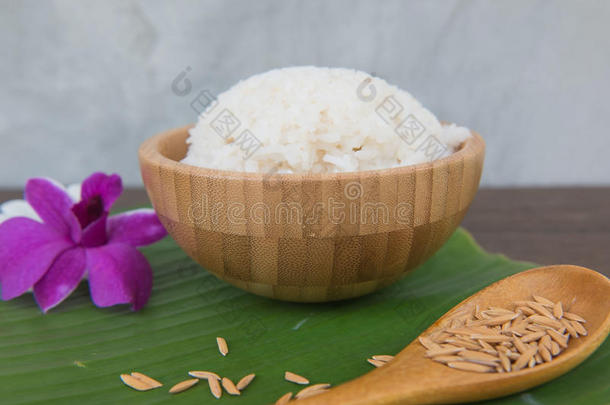 把米饭放在碗里，放在绿色的香蕉叶上，把稻谷放在勺子和兰花里。
