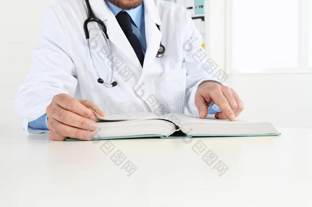 医生在办公室桌面上读一本医学书籍。 保健，