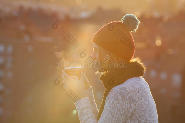 圣诞佳节的女人在日落时喝咖啡