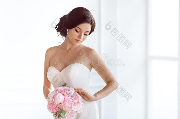 美丽的新娘。 婚礼发型化妆豪华时尚礼服和花束。