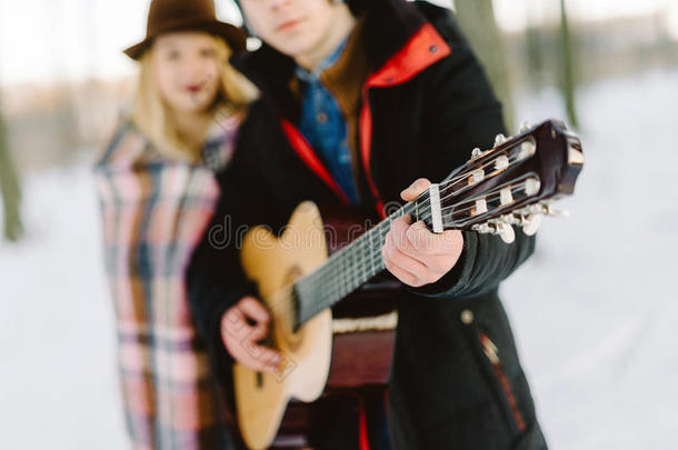 一个男人拿着吉他，和他的女朋友牵手，大气的感官时刻。 时尚时髦的夫妇在时尚的外观。 乡村W