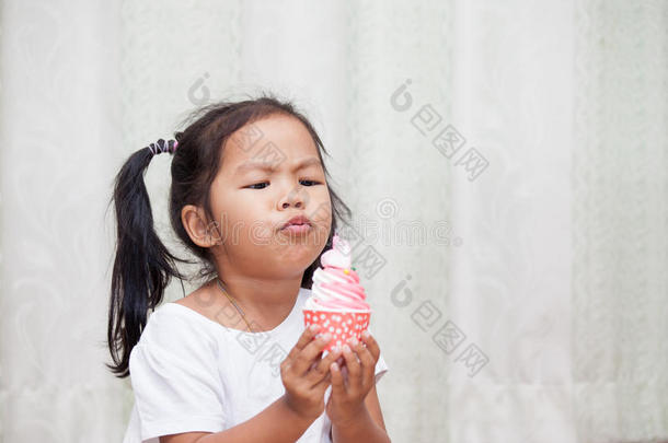 亚洲小女孩玩得很开心，吹生日蛋糕