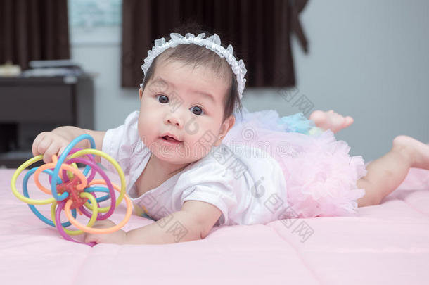 可爱的婴儿微笑，在粉红色的毯子上玩玩具