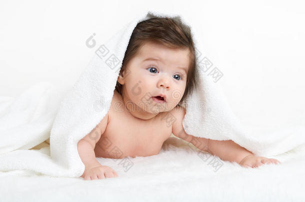 婴儿躺在白色毛巾上。 孩子在床上。 头上盖着毯子