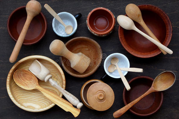 陶瓷，木制，粘土空手工碗，杯子和勺子在黑暗的背景。 陶器器皿，厨房用具。