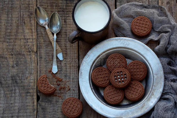 巧克力饼干与白色奶油和一杯牛奶在木制背景。