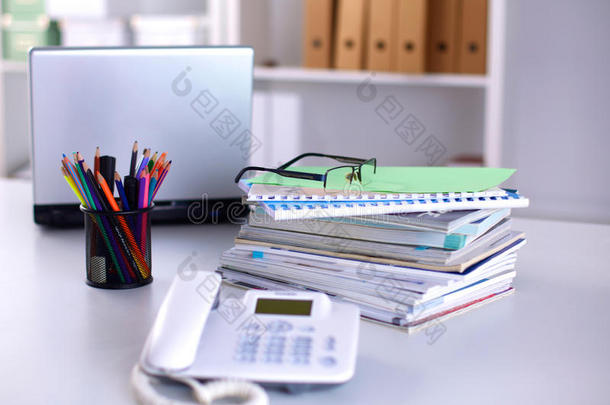 一本笔记本，笔记本电脑，钢笔，白纸文件放在办公桌后面的白色盲人桌子上