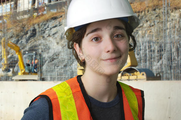 建筑工地上的女孩穿着橙色背心和白色安全帽