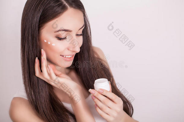 化妆品，健康和美容概念-美丽的女人在她的皮肤上涂奶油