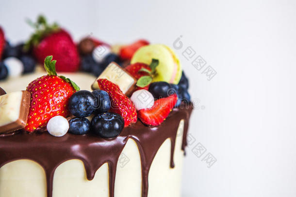 美丽的奶油色<strong>蛋糕装饰草莓</strong>，蓝莓，巧克力，马卡龙，站在白色的木桌上