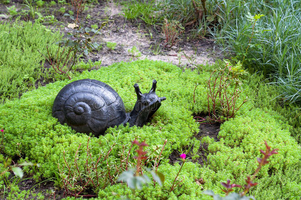 公园里的一座小雕像。 花园里装饰着<strong>蜗牛</strong>，周围是青草和鲜花