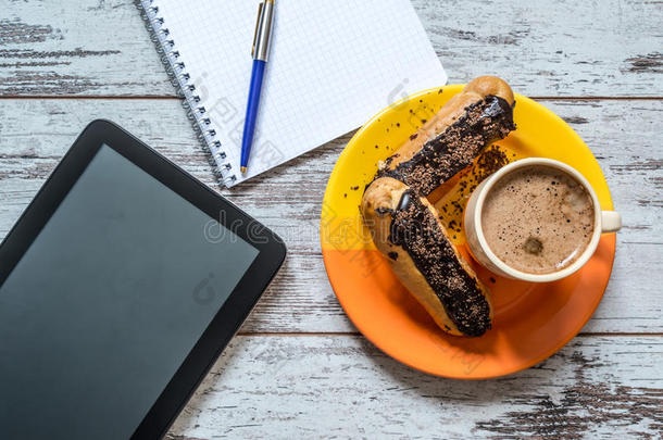 咖啡，蛋糕，巧克力，平板电脑，笔记本和笔特写在老式木制背景上。 上面的风景。