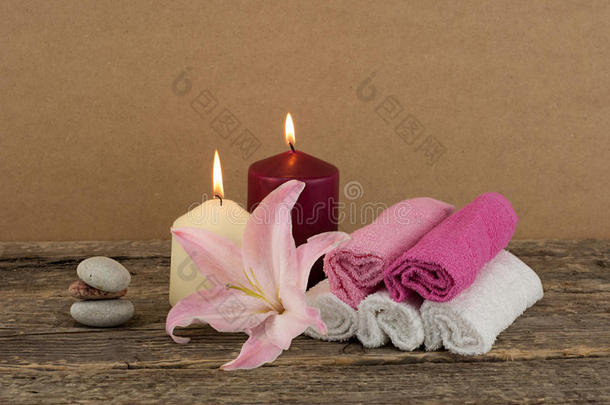 漂亮的构图，两支蜡烛，一叠温泉石和毛巾在木制背景上