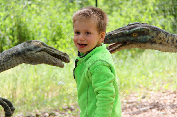 穿着绿色夹克的男孩由两个恐龙头模型