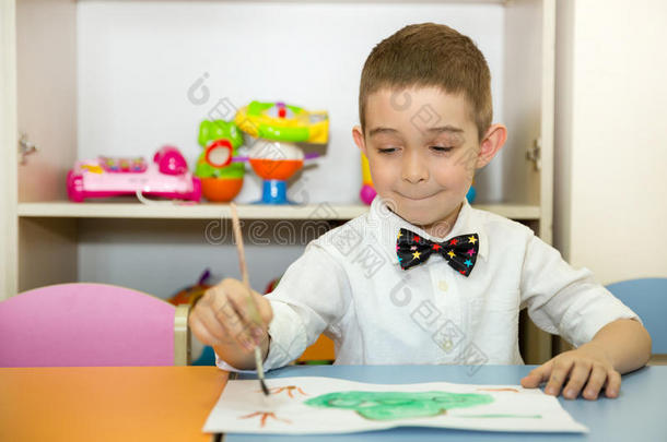可爱的小男孩在托儿所画了一把刷子和颜料。 蒙台梭利学前班幼儿园的孩子。
