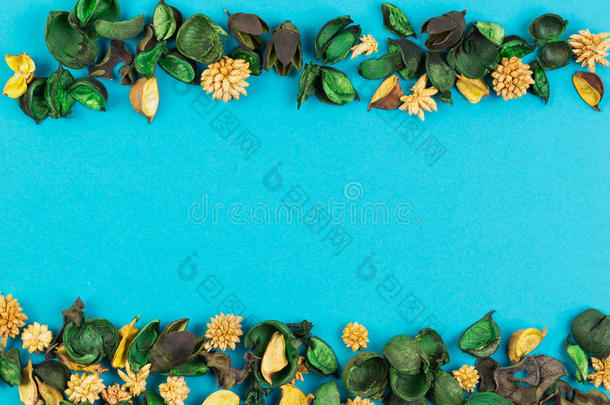 干花和叶子边框在蓝色背景上。 俯视图，平躺。
