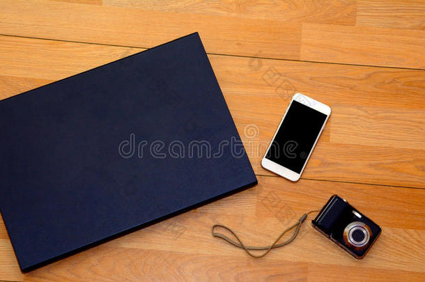 相机，封闭的笔记本电脑和木制桌子上的白色电话。