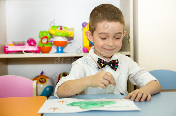 <strong>可爱</strong>的小男孩在托儿所画了一把刷子和颜料。 蒙台梭利学前班幼儿园的孩子。