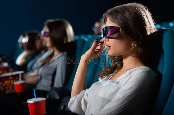 有吸引力的年轻女人在电影院里欣赏电影