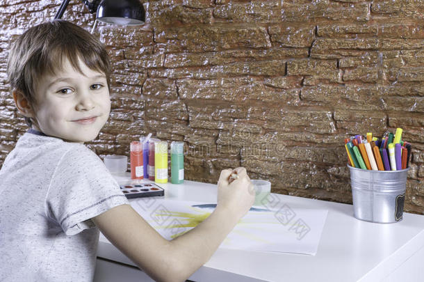 可爱的小男孩坐在桌子旁画画