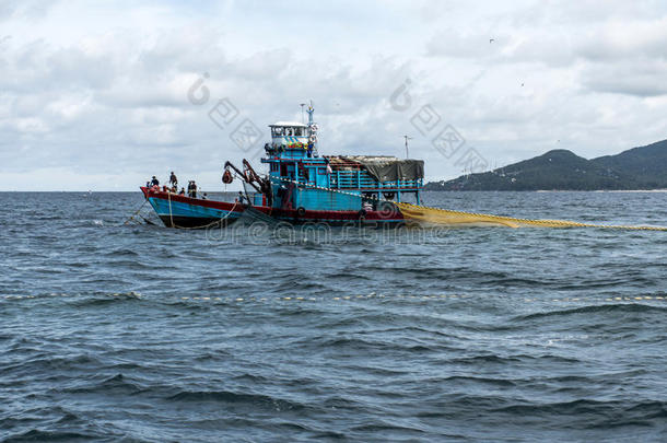 渔船大渔民用鱼网在蓝色的海洋上捕鱼