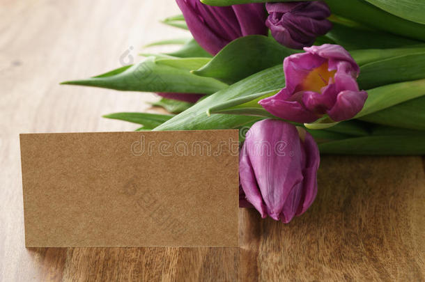 木桌上一束紫色郁金香，纸卡上有复制空间
