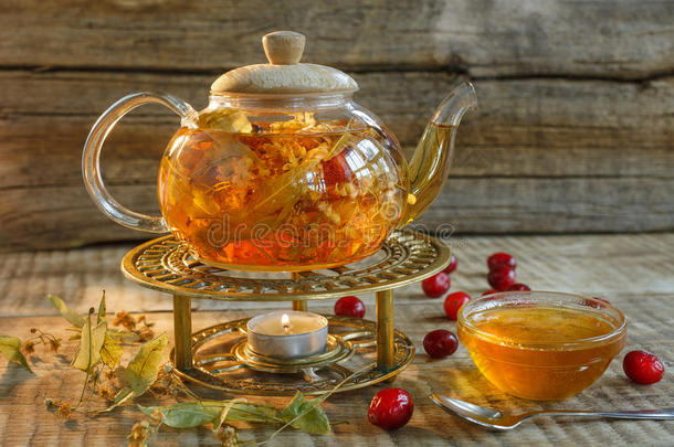<strong>玻璃</strong>茶<strong>壶</strong>与热的美味茶与柠檬，草药，。 黄色柠檬和茶。 木制背景上温暖颜色的茶<strong>壶</strong>。 草药茶