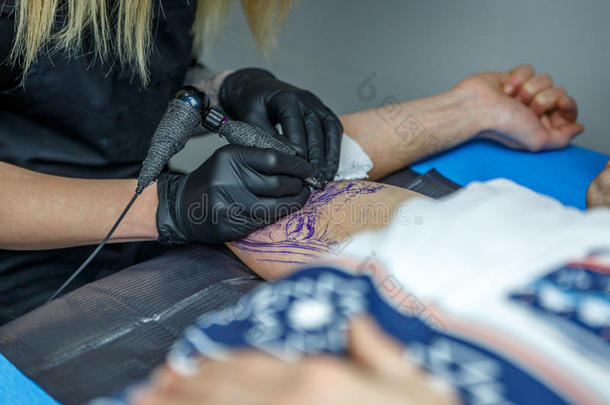 一个纹身艺术家的女人小心地纹身手臂