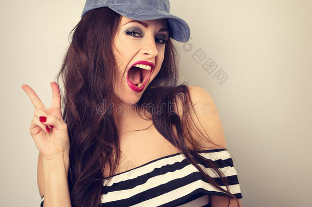 疯狂的年轻女模特戴着蓝色的帽子，用w展示了<strong>摇滚</strong>的<strong>手势</strong>