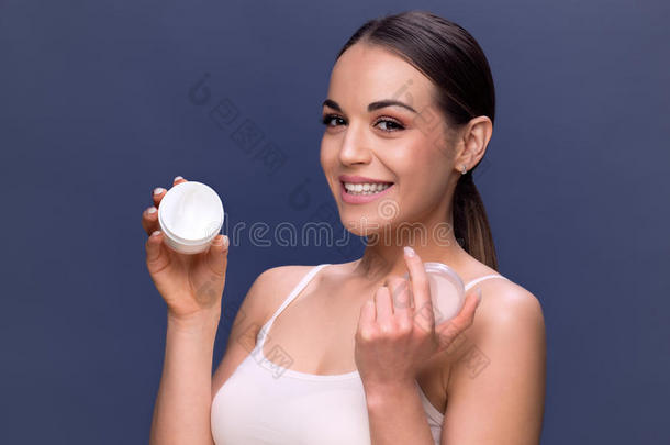 美容，人，护肤品和化妆品的概念-妇女与保湿霜在手上和面部。