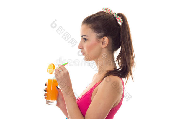 一个年轻的女孩值得<strong>侧身</strong>，拿着一杯橙汁在白色的背景上被隔离