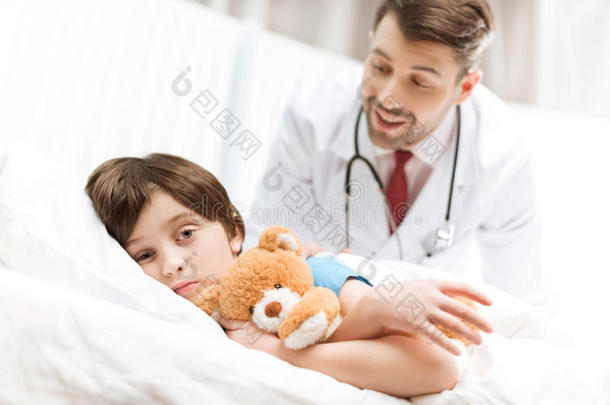 孩子病人躺在床上，身后有微笑的医生