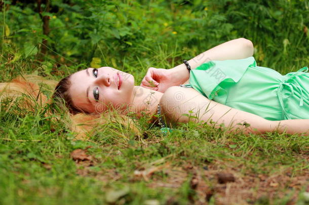 情绪化的金发女郎，在镜头里微笑，躺在草地上。
